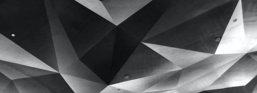 Geometric, faceted ceiling with multiple triangular panels in shades of gray and several recessed lights.
